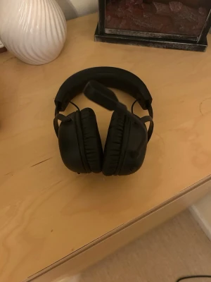 Svarta HyperX gaminghörlurar - Säljer ett par svarta over-ear gaminghörlurar från HyperX med mikrofon. Hörlurarna har mjuka, vadderade kåpor och justerbart huvudband i plast och metall. Perfekta för gaming eller streaming med bra ljudisolering och bekväm passform.
