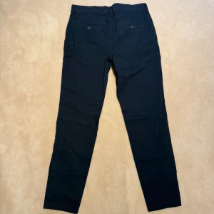 Mörkblå chinos - Snygga mörkblå chinos från Plain Units i klassisk rak modell. Nypris 1600kr mittpris 399 kr. Bra skick förutom att de har en liten fettfläcka som går att ta bort. Skriv vid frågor mvh!