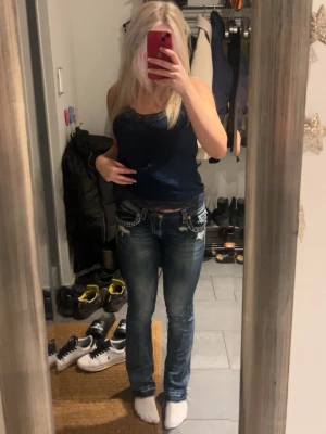 Blå Miss Me jeans med detaljer - Säljer ett par blå lågmidjade jeans från Miss Me med snygga slitningar och dekorativa fickor. Jeansen har bootcut-modell. 