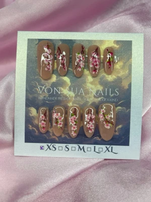 Sakura 🌸(XS);Medium Oval - Handgjorda press-on naglar i storlek XS: 14 mm, 11 mm, 11,5 mm, 10 mm, 8 mm . Naglarna har en nude glittrig bas och är dekorerade med detaljerade rosa och vita sakura samt gröna blad. Formen är medium oval och designen är elegant och konstnärlig, perfekt för dig som vill ha något unikt.