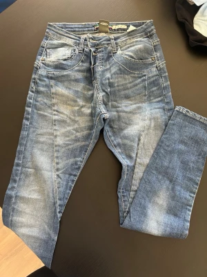 Blå please jeans med tvättade detaljer - Snygga blå slim fit jeans med slitna och tvättade detaljer för en trendig look. Klassisk femficksmodell med dragkedja och knapp i midjan. Jeansen har en smal passform och är tillverkade i mjukt denimtyg som ger bra stretch och komfort.