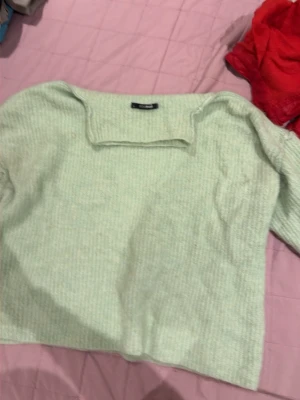 Ljusgrön stickad tröja Bik Bok - Mysig ljusgrön stickad tröja från Bik Bok med ribbad struktur och fyrkantig halsringning. Perfekt för dig som gillar en enkel men trendig look. Tröjan har långa ärmar och en avslappnad passform.