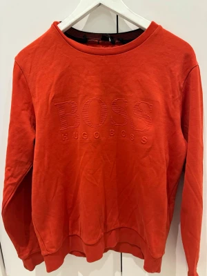 Röd sweatshirt från Hugo Boss - Röd sweatshirt från Hugo Boss med broderad logga på bröstet. 