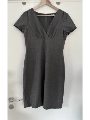 Banana Republic grå figursydd klänning, 95% ull, storlek L - Stilren grå klänning från Banana Republic i storlek L / 40-42 / 10. Klassisk modell med kort ärm och överlappande V-ringning. Dold dragkedja baktill och en slits nedtill för bekväm rörlighet. 95% ull, 5% elastan, så bra material som både andas och anpassar sig till kroppen för bästa passform. Nypris 1850:-. Mycket gott skick, som ny!