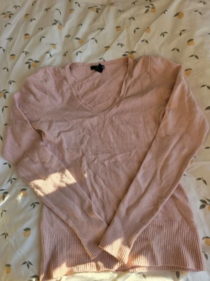 Ljusrosa stickad V-ringad tröja - H&M - S - Söt ljusrosa stickad tröja med V-ringning och långa ärmar. Tröjan har ribbade muddar vid ärmslut och nederkant, vilket ger en snygg passform. Perfekt att matcha med jeans eller kjol för en avslappnad look.