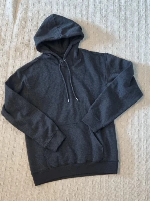 Mörkgrå hoodie från hm storlek small - Mörkgrå hoodie med huva och dragsnören. Klassisk känguruficka framtill och ribbade muddar vid ärmslut och nederkant. Tillverkad i mjukt bomullsmaterial för en skön och avslappnad look. Perfekt för chill dagar eller när du vill ha något bekvämt. Nytt plagg storlek small från hm  den är svart / grå