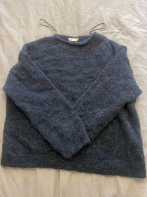 Mörkblå fluffig stickad tröja  - Mysig mörkblå stickad tröja från C i storlek M. Tröjan har en fluffig och mjuk struktur med rund halsringning och långa ärmar. Perfekt för kalla dagar när du vill ha något riktigt bekvämt och snyggt.