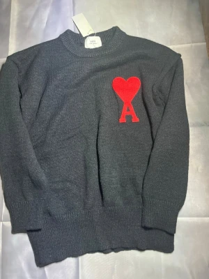 Svart stickad tröja från Ami - Mörkgrå stickad tröja från Ami med rund halsringning och ribbade muddar. Perfekt för dig som gillar stilrena detaljer och vill ha något extra i garderoben. Storlek M. Skriv vid funderingar och pris kan dirkuteras vid snabb affär.