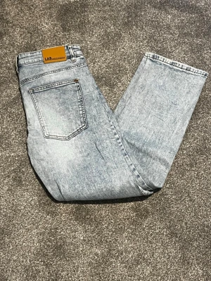 Sprillans nya Ljusblå raka jeans från Levi’s - Säljer ett par ljusblå raka jeans från Levis archive med klassisk femficksdesign och läderpatch bak i midjan. Jeansen har en tvättad look och är tillverkade i bomull för en skön och avslappnad stil. de här jeansen är lite större i storleken och passar alla som är mellan 160 cm och 175 cm lång. Perfekta till vardags med sneakers eller skor i sommar. Vid minsta fundering eller fråga var vänligen att meddela mig. Med vänliga hälsningar Eric