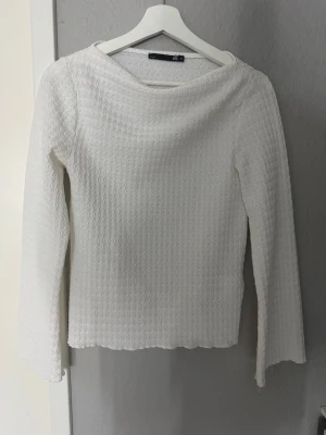 Vit långärmad topp med struktur - Säljer en vit långärmad topp med vågig struktur i tyget som syns på bild tre. ett lätt och stretchigt material. Den är väldigt snygg och kan användas till vad som. Säljs för den har inte kommit till användning.