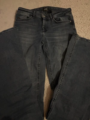 Mörkblå jeans från ONLY - Säljer ett par mörkblå jeans från ONLY med klassisk femficksdesign och utsvängda ben. Jeansen har en snygg tvättad look och är tillverkade i ett mjukt denimtyg som sitter skönt. Perfekta till en avslappnad stil och passar till det mesta. De är i storleken TALL 34