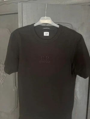 Svart t-shirt från C.P. Company - Snygg svart t-shirt från C.P. Company med diskret broderad logga på bröstet. Tillverkad i 100% merceriserad bomull för en mjuk och lyxig känsla. Klassisk rund hals och korta ärmar, perfekt till alla outfits.