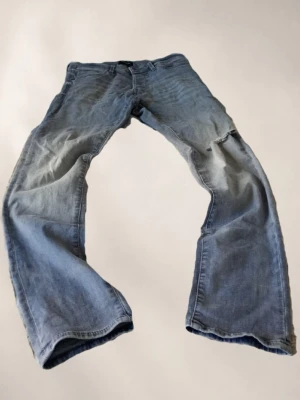 Gråa jeans jack n Jones slim fit - Säljer ett par gråa jeans med slitningar och lätt tvättad look. Jeansen har klassisk femficksdesign och vida ben. Perfekta för dig som gillar en avslappnad och retro stil.