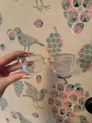 Transparenta fyrkantiga glasögon utan förstärkning - Säljer ett par trendiga glasögon med transparent båge och fyrkantig form. Glasögonen har en clean och modern look som passar till alla outfits. Perfekta för dig som vill ha en stilren accessoar med edge. UTAN FÖRSTÄRKNINGAR