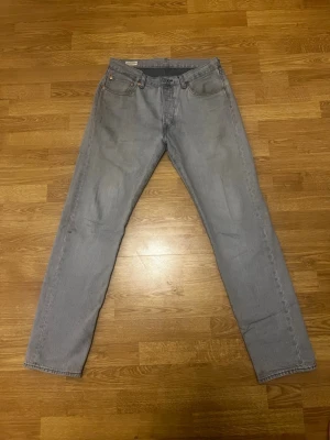 Grå Levi's Premium raka jeans - Säljer ett par grå Levi's Premium jeans med rak passform och klassisk femficksdesign. Jeansen har knappgylf och är tillverkade i slitstarkt denimtyg. Perfekta för en avslappnad och stilren look.