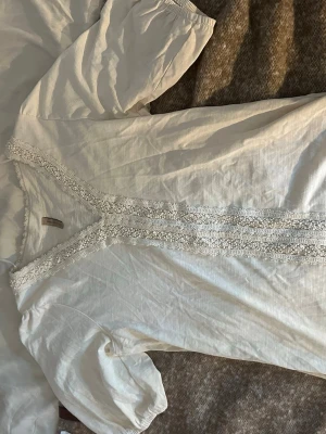 Vit blus med spetsdetaljer från Soyaconcept  - Söt vit blus från Soyaconcept med puffiga ärmar och elastiska muddar. Fina spets- och pärldetaljer. Tillverkad i ett mjukt, tunt tyg som känns luftigt och bekvämt. Helt nya och aldrig använt super skick!!🥰