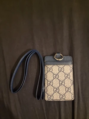 Plånbok med band - Elegant plånbok med avtagbart handledsband i stilren design. Plånboken har flera fack för kort, sedlar och mynt, vilket gör den både praktisk och snygg för vardag och fest. Tillverkad i slitstarkt material med exklusiva detaljer och ett tidlöst mönster som ger ett lyxigt intryck. Perfekt för dig som vill ha ordning på dina viktigaste tillhörigheter i ett smidigt format.