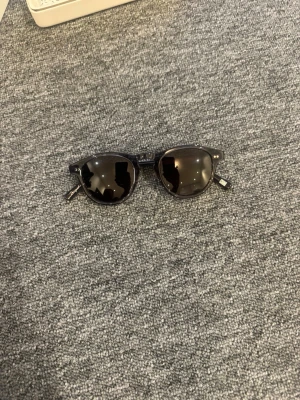 Chimi 002 runda solglasögon - Snygga svarta solglasögon med rund form och mörka glas. Kommer med ett vitt hårt fodral och ett mönstrat tygfodral för extra skydd. Perfekta för soliga dagar och ger en cool vibe till din outfit. Chimi 002 ginger.
