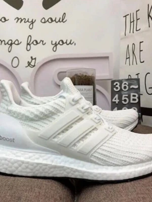 Vita Adidas Ultra Boost sneakers - Säljer ett par helvita Adidas Ultra Boost sneakers med stickad ovandel och klassiska tre ränder på sidan. Skorna har en bekväm Boost-sula och en sportig, modern look. Perfekta för dig som gillar stilrena och bekväma sneakers.