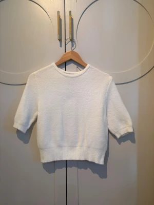 ☁️Vit stickad kortärmad tröja☁️ - Säljer en stilren vit stickad tröja med korta ärmar och rund halsringning. Tröjan har ribbstickade muddar vid ärmslut och nederkant, vilket ger en snygg och enkel look. Perfekt att matcha med jeans eller kjol för en clean stil.