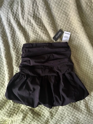 Svart tubtopp från Boohoo - Trendig svart tubtopp från Boohoo med volang nedtill. Den är helt ny med prislapp och helt oanvänd av mig då den var för liten för mig💓