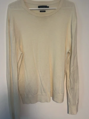 Beige merinoulltröja från Riley - Säljer en stilren beige stickad tröja från Riley i mjuk merinoull. Tröjan har rund halsringning, långa ärmar och ribbade muddar. Perfekt för lager-på-lager och enkel att matcha med olika outfits. Den är lite liten i storleken så skulle säga att den passar mer som en S - M i storlek 