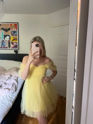Klänning  - Supersöt gul kortklänning i tyll med offshoulder-ärmar och volangdetaljer. Klänningen har en hjärtformad urringning och fluffig kjol som ger en prinsesskänsla. Perfekt för sommarens alla tillfällen! Bara använd en gång då jag inte kommer hitta tillfälle att använda den igen. Från Lace & beads.