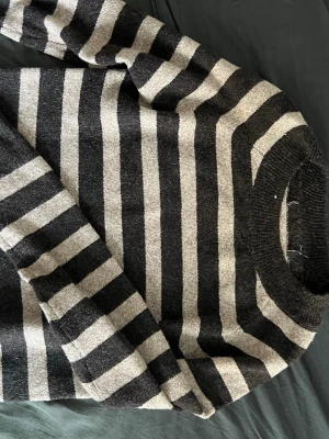 Randig stickad tröja svart/grå - Säljer en stickad tröja med breda svarta och gråa ränder. Tröjan har rund halsringning och långa ärmar. Materialet känns mjukt och mysigt, perfekt för kyliga dagar. Enkel och stilren design som passar till det mesta. Från veromoda 