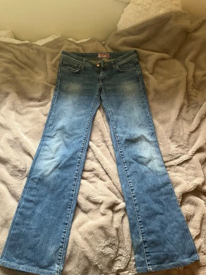 Lågmidjade bootcut jeans  - Säljer ett par blå lågmidjade bootcut jeans från fit & Flary i storlek 29. De har lite slitningar längst ner på baksidan av varje ben  