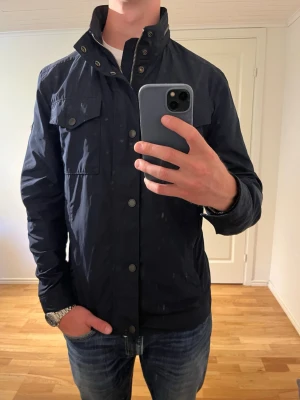 Mörkblå J.Lindeberg Fieldjacka  - Säljer denna sjukt snygga fieldjackan från J.Lindeberg⭐️ Färgen är mörkblå och storleken är L✅ Den har inga defekter och skicket är utomordentligt🙌🤝 Sjukt najs passform och passar perfekt till hösten☀️🙌 Tveka inte på att höra av er dig vid minsta fråga eller fundering😊