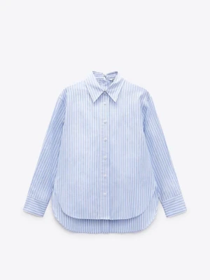 Blåvit randig skjorta från Zara - Klassisk blåvit randig skjorta från Zara med lång ärm och knappar framtill. Skjortan har en avslappnad passform, bred krage och rundad nederkant. Tillverkad i mjuk bomull som känns skön mot huden. Perfekt för en clean och stilren look.