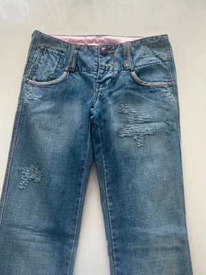 Lågmidjade bootcut jeans - Snygga blå jeans. De är bootcut och lågmidjade med slitna detaljer längs benen, kan absolut fixa fler bilder om det önskas. Säljer eftersom de inte passade mig, men sitter som en xs!🫤