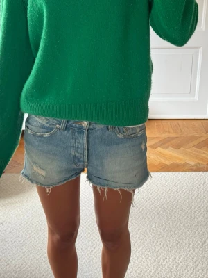Levi's ljusblå jeansshorts med fransar - Ljusblå jeansshorts från Levi's med råa fransade kanter och slitna detaljer. Klassisk femficksmodell med knapp och dragkedja framtill. Perfekta för en avslappnad och trendig look.