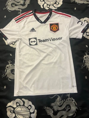 Manchester United Bortatröja 22/23 Martinez #6 - Säljer en officiell Manchester United bortatröja från säsongen 2022/23 med Lisandro Martinez på ryggen nummer 6.  Skick: Nära Nyskick.  Storlek: S.  Spelare: Martinez #6 Kan hämtas upp i Gnesta annars skickas den via posten samma dag som beställningen är lagd. Vid frågor eller prisförslag skicka DM!