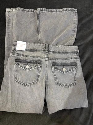 Low waist wide jeans ljusgrå - Säljer ett par trendiga ljusgrå low waist wide jeans från Gina Tricot Materialet. Helt nya med lappen kvar, säljer då de ej kommit till användning. 