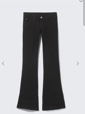 Svarta low bootcut jeans från Weekday - Säljer ett par svarta bootcut jeans från Weekday/cheap Monday. med klassisk femficksmodell och en lila patch bak. Jeansen har utsvängda ben och är tillverkade i ett stretchigt material som sitter snyggt på kroppen. Perfekta för dig som gillar retrovibbar och streetstyle. Storlek 26/34
