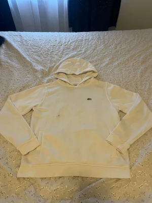 Lacoste hoodie vit  - Säljer min Lacoste hoodie som jag inte längre använder, den passar med i varenda outfit. Däremot har den även fickor i varsin sida och märket ligger vid bröstet. För dig som är 164 så passar den dig perfekt. 