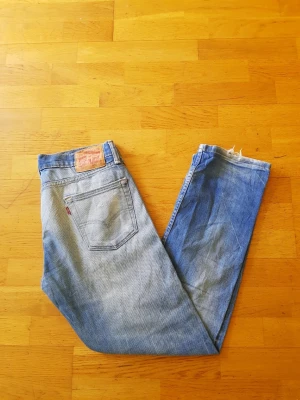 Levi's 513 ljusblå Jeans - Säljer ett par klassiska Levi's 513 jeans i ljusblå denim med vintagekänsla. Jeansen har raka ben, fem fickor och den ikoniska röda Levi's-lappen på bakfickan. Materialet är 100% bomull och passformen är relaxed. Perfekta för en avslappnad streetstil.