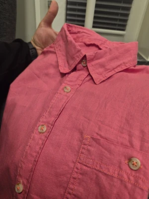 Rosa Linnen Blend skjorta från Dressmann L - Snygg rosa skjorta med korta ärmar och klassisk krage. Skjortan har knäppning framtill och en bröstficka med knapp. Perfekt för dig som vill sticka ut med färg. Tillverkad i bomull för en skön känsla.