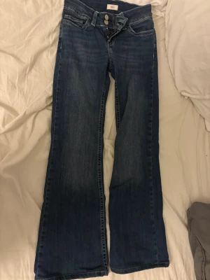 Blå bootcut-jeans från nelly - Snygga blå bootcut-jeans från nelly med klassisk femficksdesign och coolt broderi på bakfickan. Jeansen har en lätt tvättad look och vida ben, perfekta för en avslappnad och trendig stil.