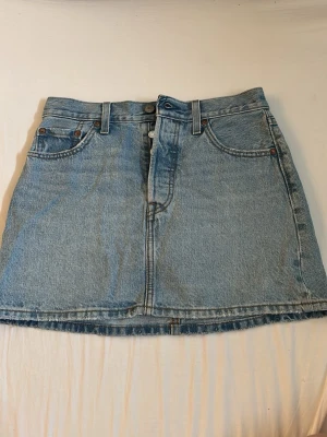 Levi's ljusblå jeanskjol Icon Skirt!!! - Ljusblå jeanskjol från Levi's Premium, modell Icon Skirt. Klassisk femficksdesign med knapp samt bälteshällor. Rak passform och kort längd, perfekt till sneakers eller boots.