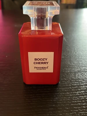 Boozy Cherry parfym från Pandora Scents - Upptäck Boozy Cherry från Pandora Scents – en parfym i en snygg, röd fyrkantig flaska med genomskinligt lock. Doften har en lyxig och ungdomlig känsla, perfekt för dig som gillar fruktiga och intensiva toner. Flaskan är tillverkad i glas och har en modern design.