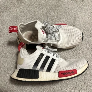 Adidas NMD R1 vita sneakers - Snygga Adidas NMD R1 sneakers i vitt meshmaterial med svarta och röda detaljer. 