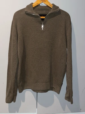 Olivgrön stickad halvzip-tröja Jack&Jones - Snygg olivgrön stickad tröja med halv dragkedja och hög krage. Tröjan har lång ärm och är tillverkad i ett mjukt, strukturerat material. Perfekt för lager-på-lager och enkel att matcha med jeans eller chinos. Storlek M passar L. Från Jack&Jones