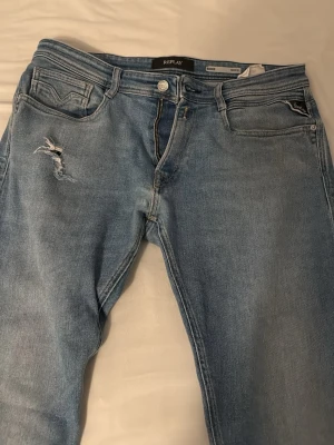 Ljusblå jeans från Replay - Snygga ljusblå jeans från Replay med slitning och hål på ena låret. Klassisk femficksmodell med raka ben och normal midja. Jeansen har en avslappnad vibe och är tillverkade i bomull för skön känsla.