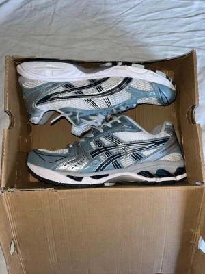 Asics Gel Kayano 14 - Asics Gel Kayano 14 Fjord Grey, mycket bra skick, använda fåtal gånger, endast lite smuts på vissa ställen som nog går att tvätta. Storlek 43.5. Box (skadad) medföljer.