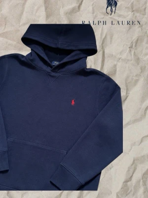 Ralph lauren hoodie - Snygg mörkblå hoodie från Ralph Lauren med klassisk röd broderad logga på bröstet. Hoodien har huva, känguruficka och ribbade muddar. Tillverkad i mjuk bomull för en skön och avslappnad stil. Skick 9/10 inga defekter med minimala användningsspår🙌💯💯storlek XS