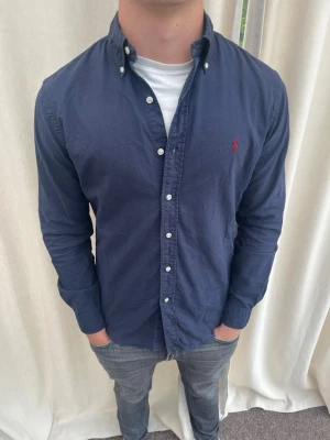 Mörkblå skjorta från Ralph Lauren - Riktig snygg skjorta från Ralph Lauren. Strl M, personen på bilden är 184 cm lång. Skicka gärna prisförslag. Kika in min profil för mer schyssta plagg 