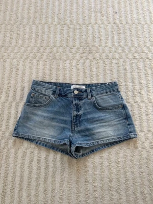 Blå jeansshorts från Pull&Bear - Klassiska blå jeansshorts från Pull&Bear med fem fickor, bälteshällor och knappgylf. Shortsen har en lätt tvättad look och normal passform. Nästan aldrig använda, storlek 38