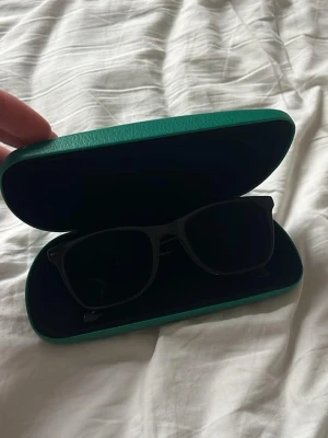 Svarta solglasögon i klassisk modell - Snygga svarta solglasögon med styrka med klassisk, fyrkantig båge. Kommer i ett stilrent grönt fodral. Perfekta för att lyfta din look med en tidlös accessoar.